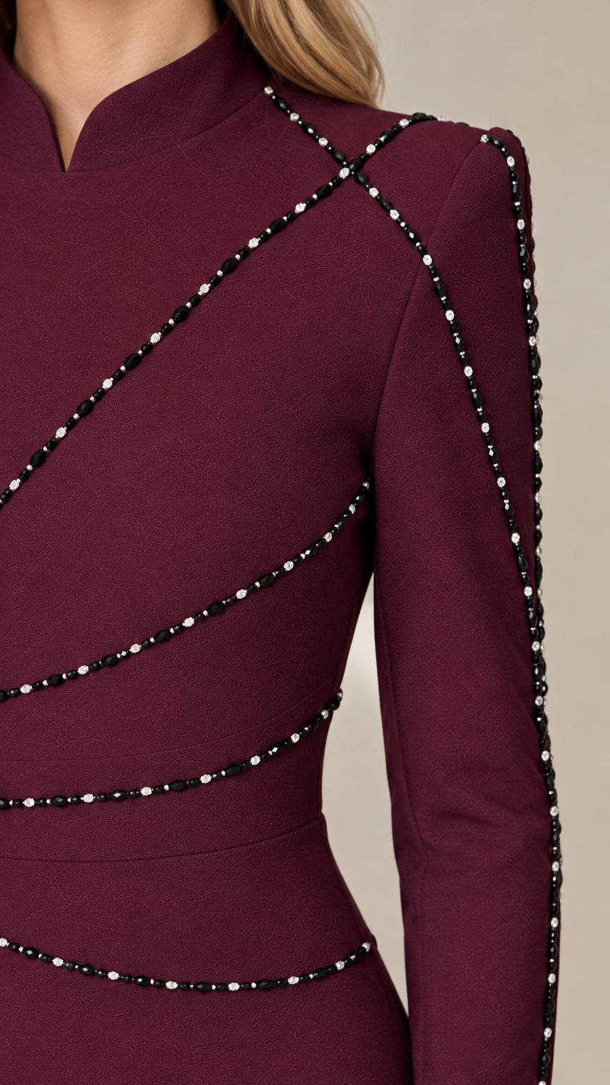 Close-up detail of neckline and diagonal beaded embellishments on burgundy dress