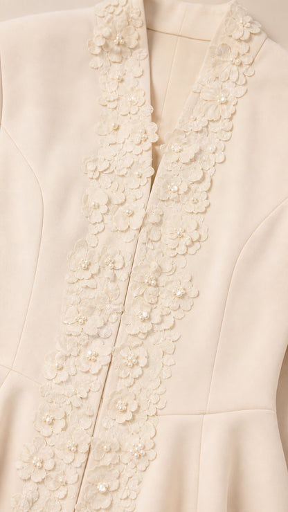 Close-up of ivory jacket neckline featuring 3D floral appliqué and pearl bead details