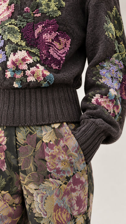 Close-up detail of intricate floral knit embroidery and trousers fabric texture