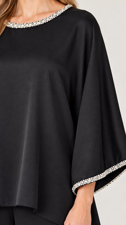 Close-up detail of sparkling crystal-beaded trim on neckline and sleeve cuffs