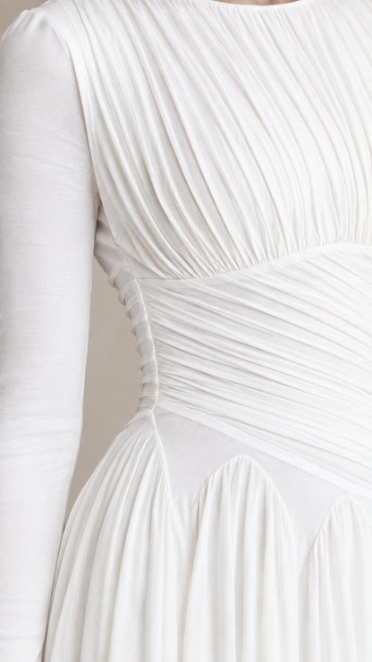 Close-up detail of textured pleating and waist construction on white dress