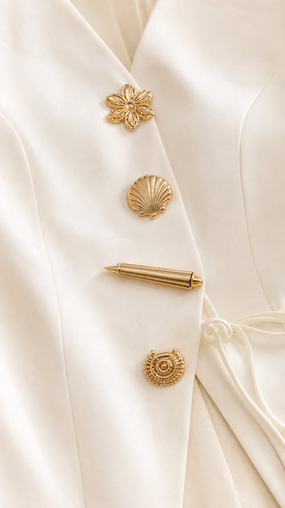 Close-up detail of ornate sculpted gold novelty buttons on the ivory tailored jacket top