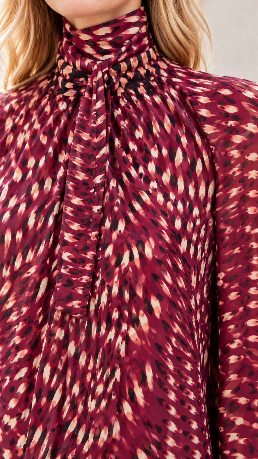 Close-up of high tie neckline and abstract print on Burgundy dress