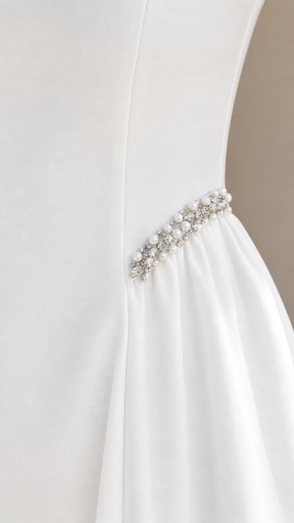 Close-up detail of pearl and crystal beaded trim on side waist of white dress