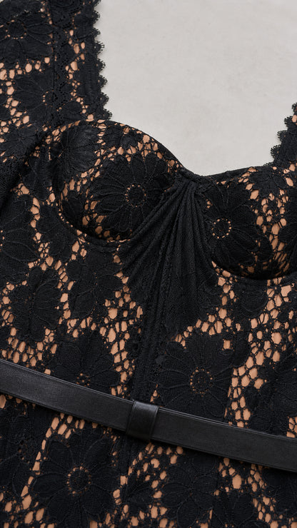 Close-up detail of sweetheart neckline, lace fabric, and waist belt on black dress