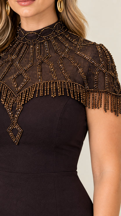 Close-up detail of geometric beadwork and fringe trim on sheer illusion neckline