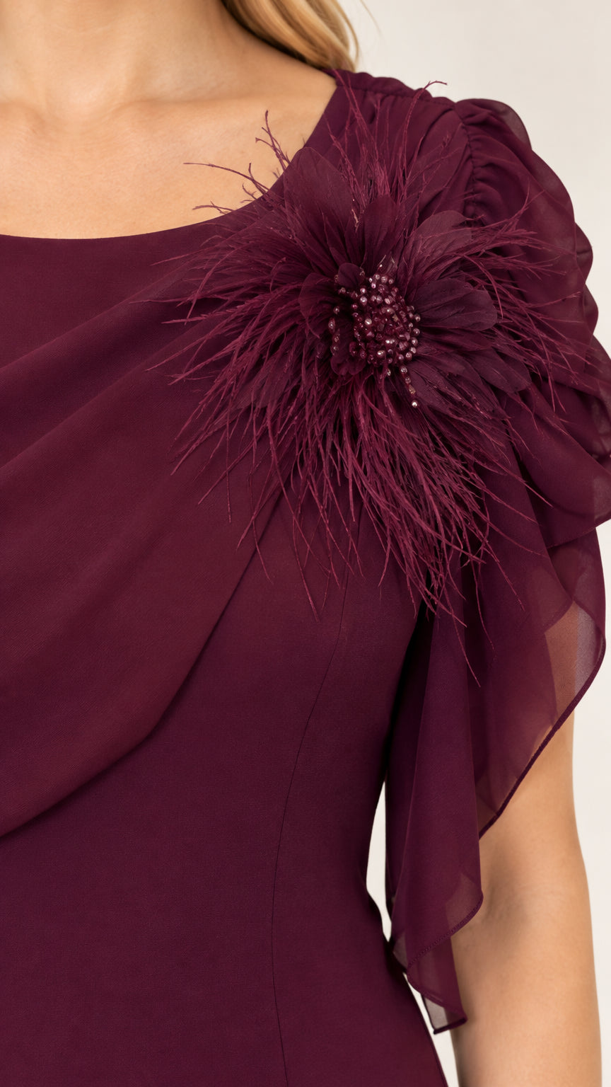 Close-up detail of burgundy draped chiffon neckline and feathered floral shoulder corsage