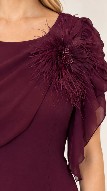Close-up detail of burgundy draped chiffon neckline and feathered floral shoulder corsage