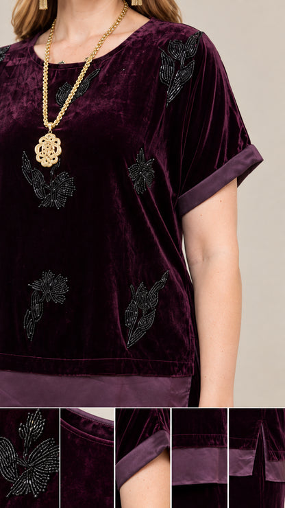 Close-up detail of beaded floral embellishments, satin cuff, and hem side slit on Plum velvet top