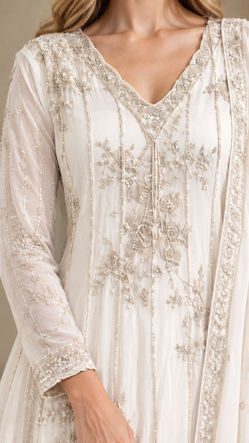 Close-up detail of intricate silver-tone embroidery on the bodice and neckline of white dress