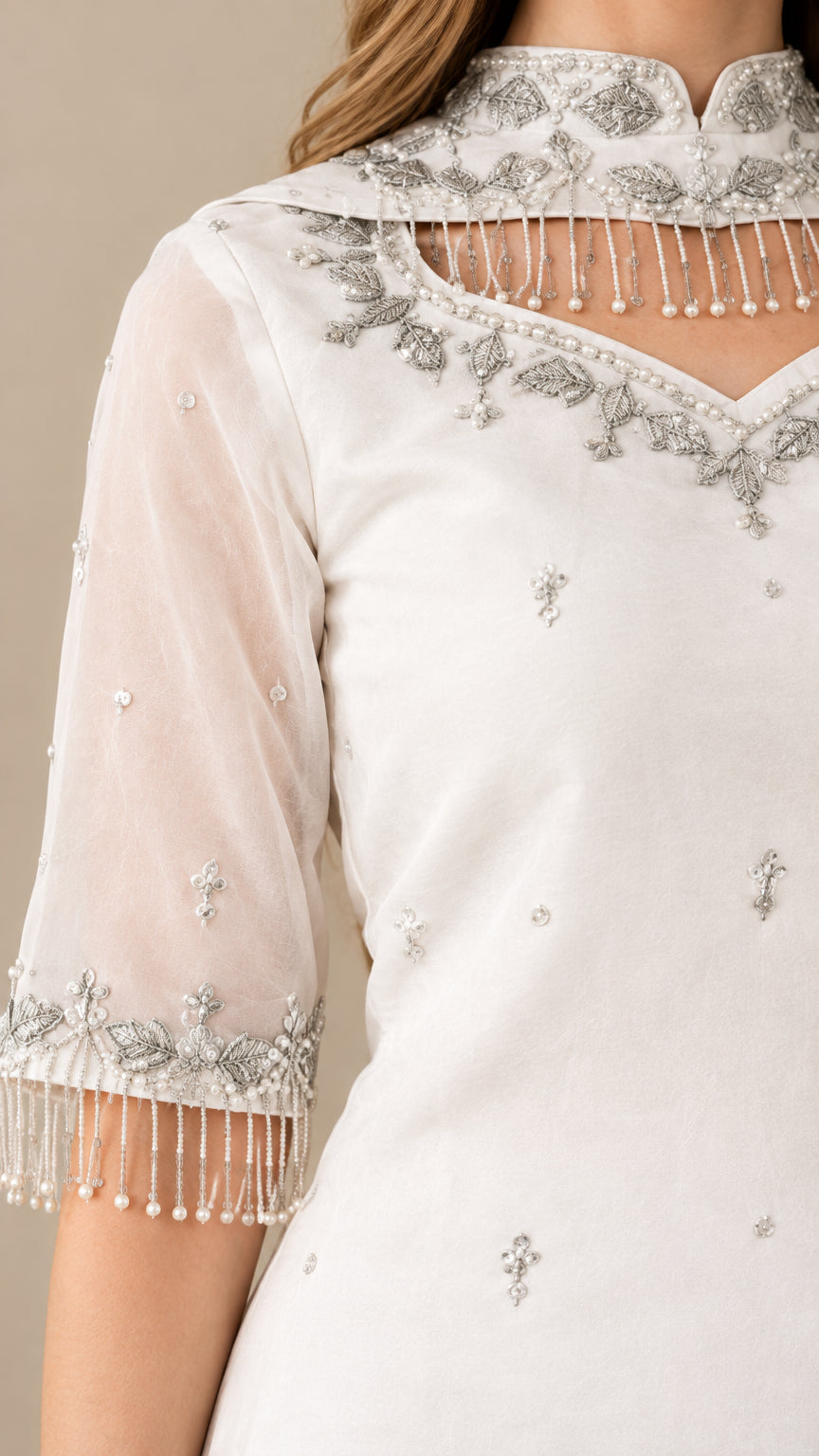 Close-up of beaded fringe hem and neckline embroidery on sheer white sleeve