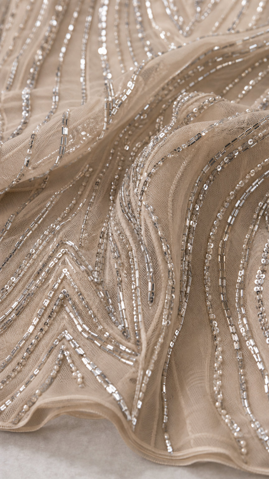 Close-up detail of geometric silver sequin and bead embroidery on sheer mesh fabric