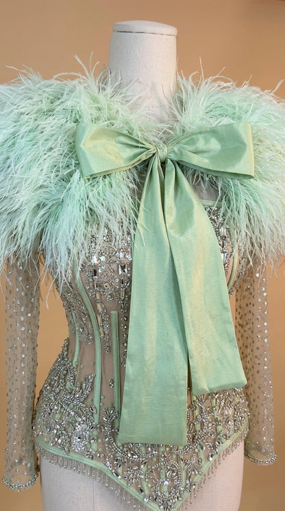 Close-up of mannequin showing intricate sequin corset bodice and mint feather bow neckline