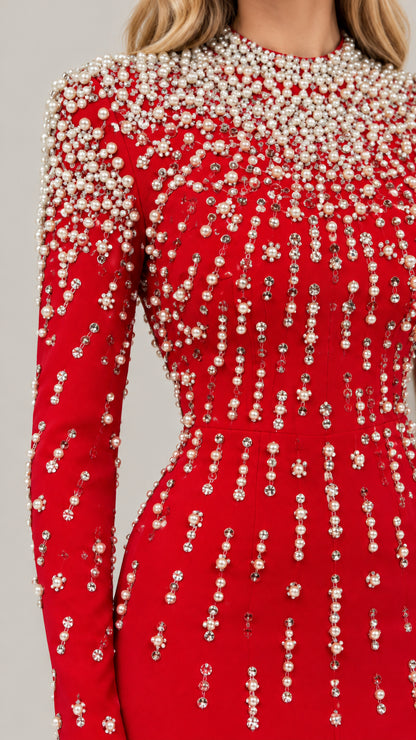 Close-up detail of cascading pearl and rhinestone embellishments on red fabric