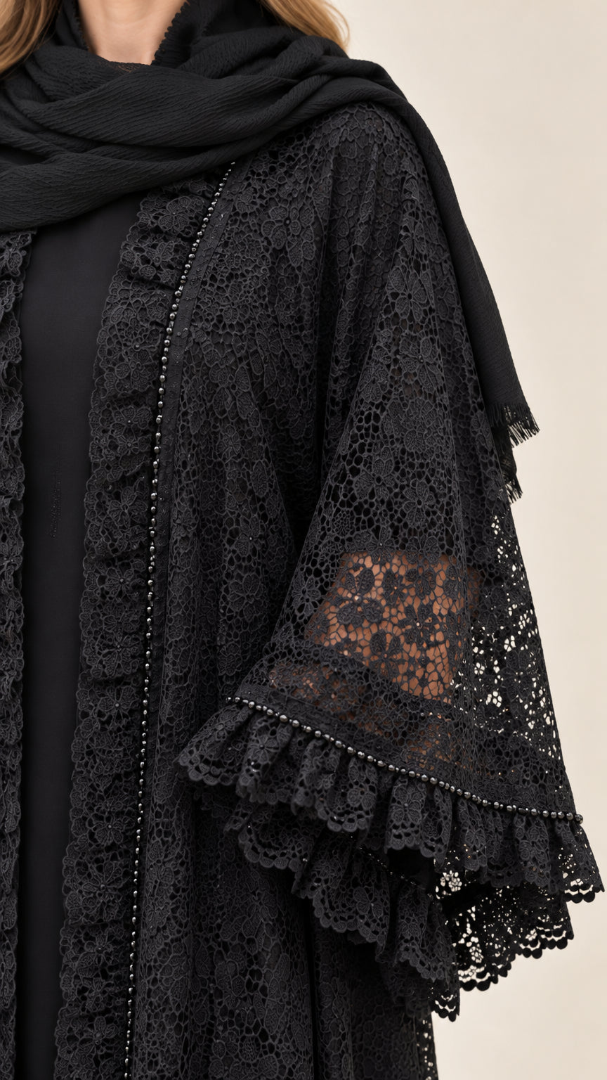 Close-up detail of textured black floral lace, delicate trim, and tiered ruffle bell cuffs