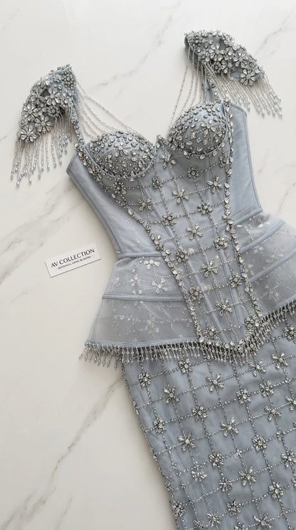 Close-up flat lay of dusty blue corset bodice with beadwork and fringe shoulder strap