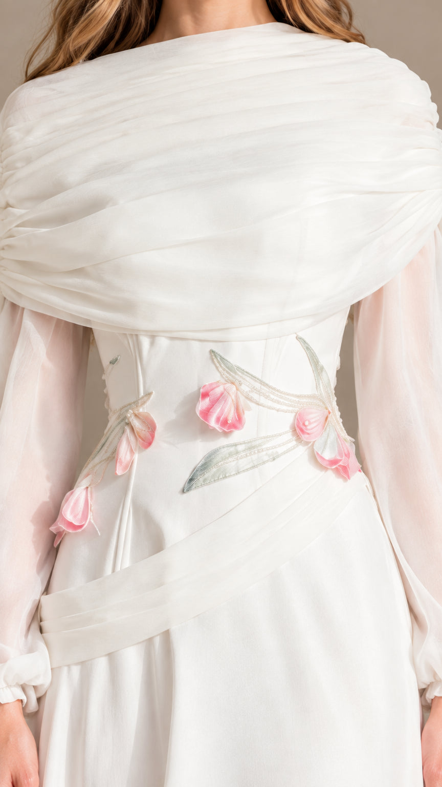 Close-up detail of draped neckline and floral embroidery at the waist of white dress