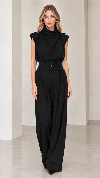 Model wearing black sleeveless drape neck wide leg belted jumpsuit