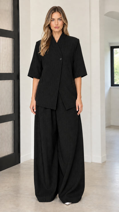 Front full-length view of model wearing Black asymmetric blazer and wide-leg pant set