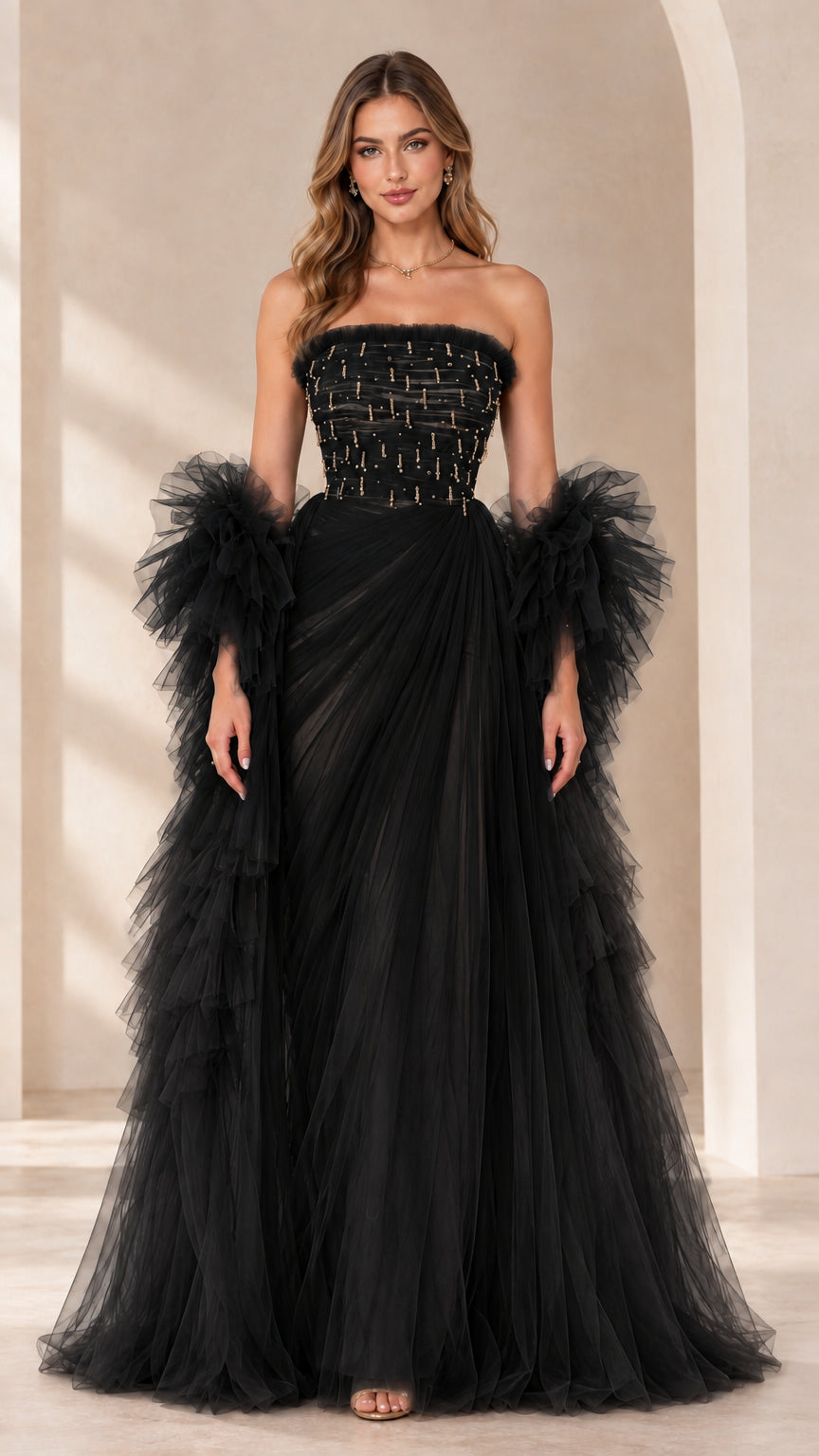 Full-length view of black strapless beaded tulle evening gown with ruffled sleeve wraps