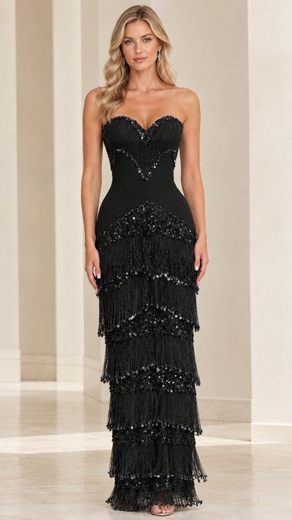 Front view of model wearing black strapless sweetheart tiered fringe maxi gown