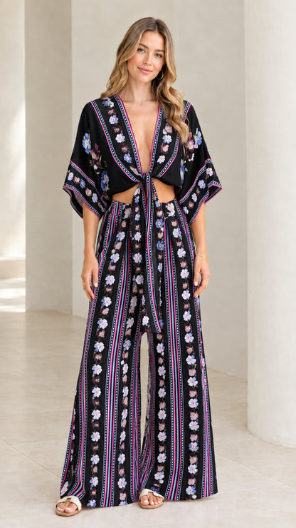 Model wearing black and purple floral stripe tie-front top and wide-leg pants set