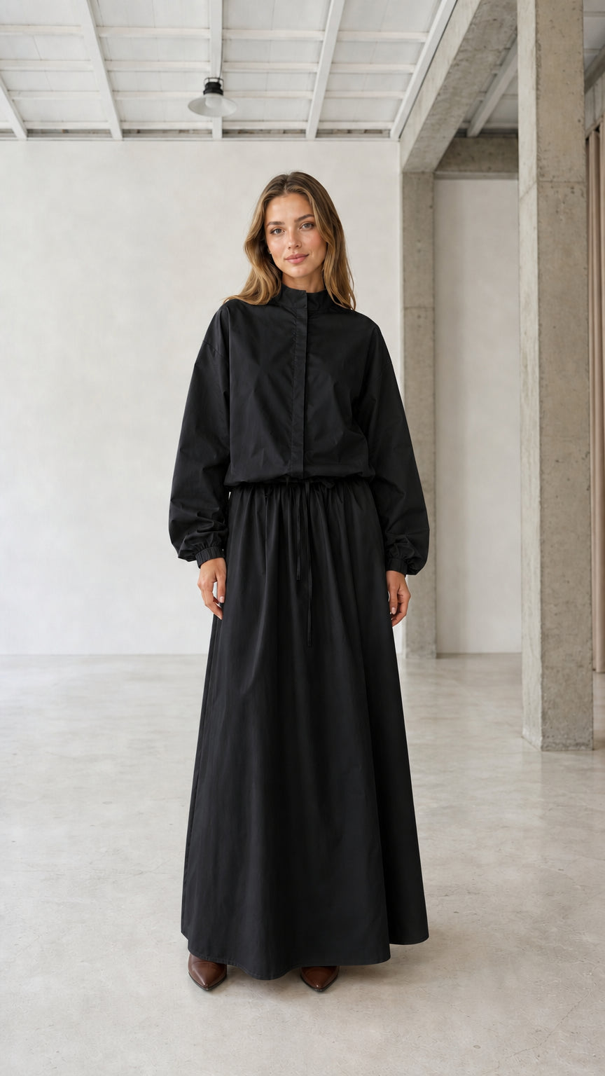 Front view of woman wearing black long sleeve stand collar drawstring maxi dress