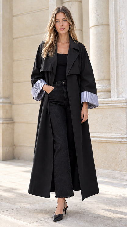 Model wearing black maxi trench coat with pinstripe cuff accents