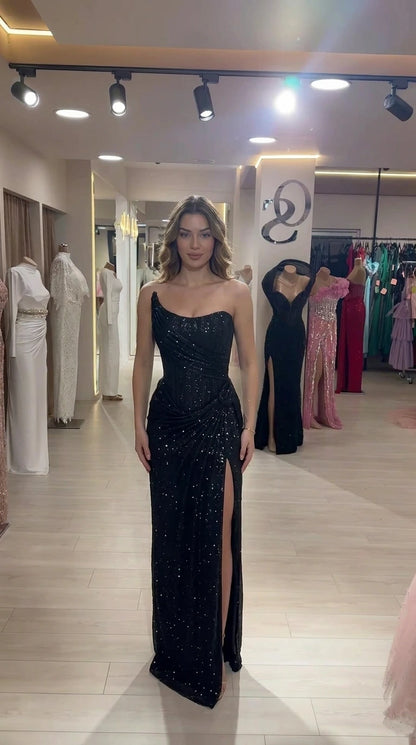 Model wearing black one-shoulder sequin evening dress with front slit