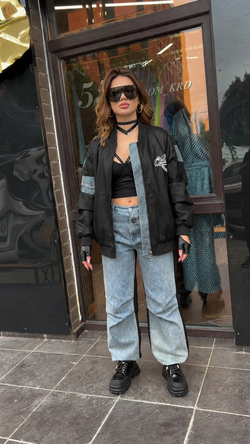 Full-length view of black faux leather bomber jacket with denim contrast accents