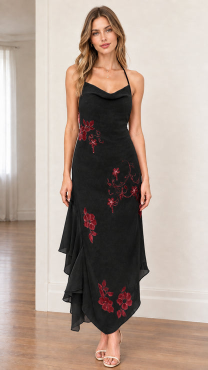 Model wearing black halter cowl neck asymmetrical dress with red floral accents