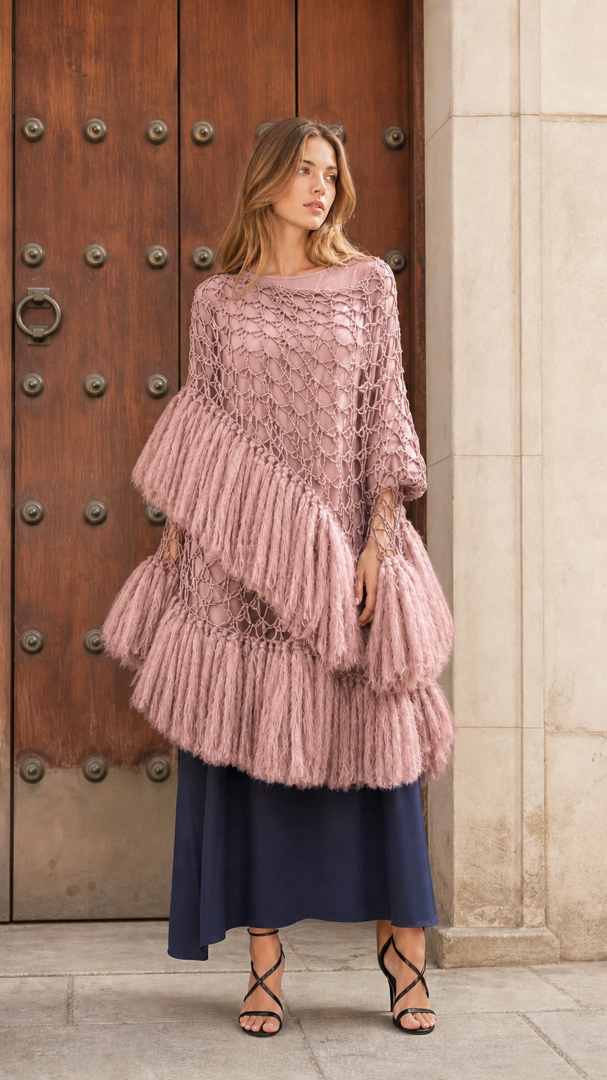Front view of dusty pink tiered fringe crochet poncho top over a dark blue underlayer