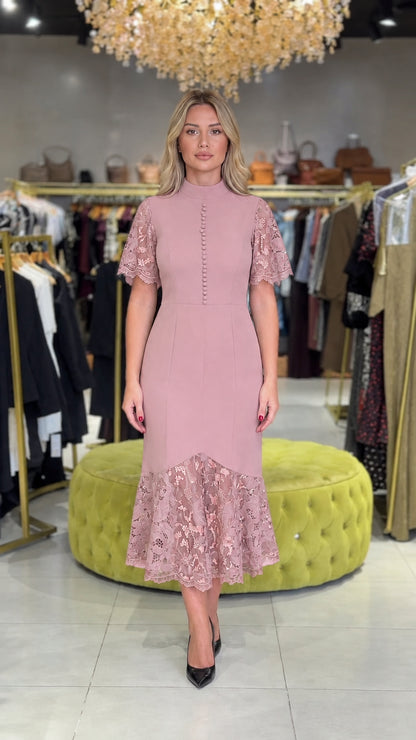 Model wearing dusty pink mock neck midi dress with lace sleeves and flounce hem