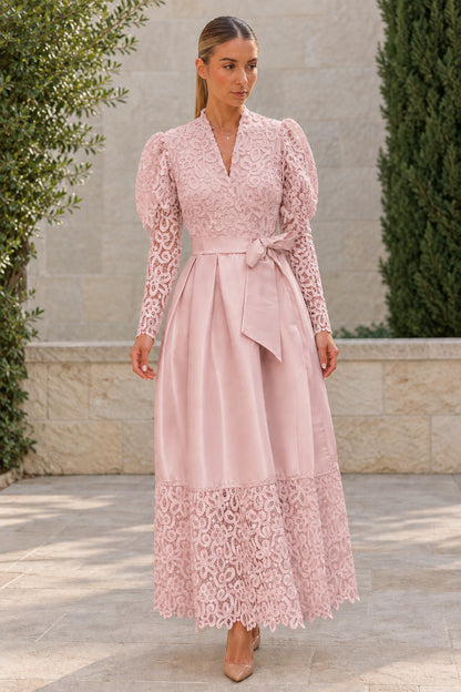 Woman wearing dusty pink lace bodice belted satin maxi dress with lace hem
