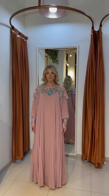 Woman wearing dusty pink pleated maxi gown with embellished neckline