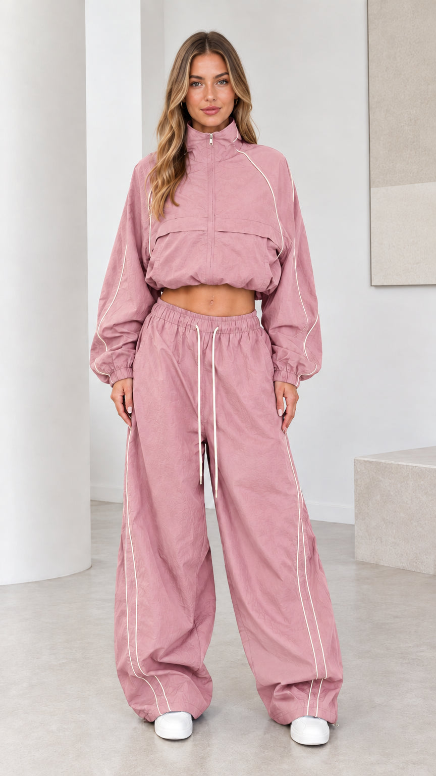 Front view of model wearing dusty pink cropped windbreaker and parachute pants set