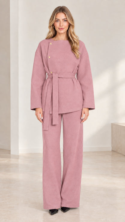 Full-length studio shot of model wearing dusty rose asymmetrical belted pant set