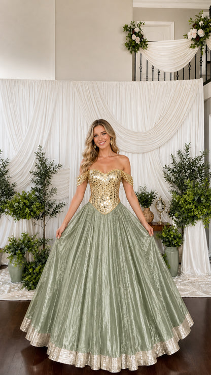 Model wearing sage green pleated ball gown with gold embellished bodice
