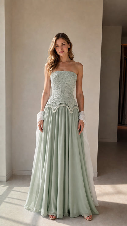 Model wearing sage green strapless beaded corset evening gown with white wrap