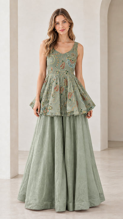 Front view of model wearing sage green embroidered peplum top and pants set