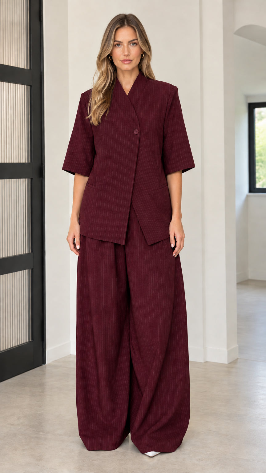 Front full-length view of model wearing Burgundy asymmetric blazer and pant set
