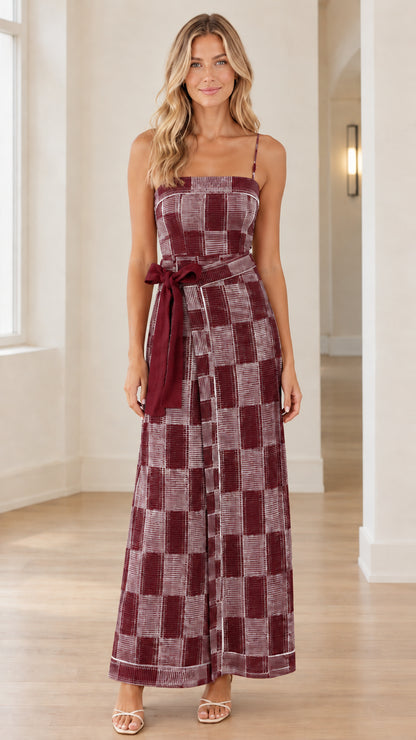 Front view of woman wearing burgundy and white checkered wide-leg jumpsuit with matching belt