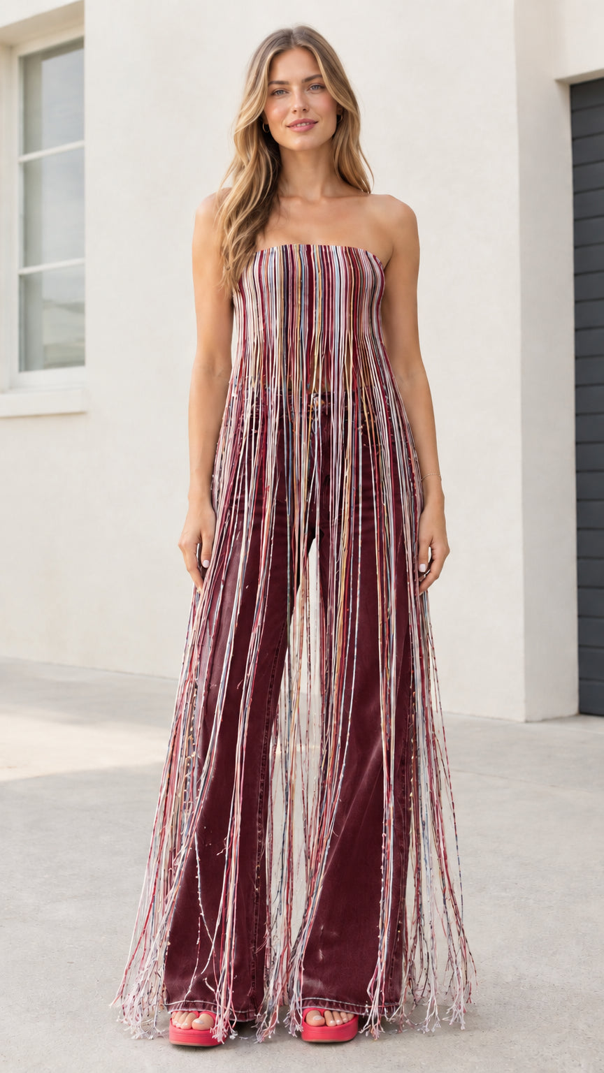 Model wearing multicolor burgundy striped maxi fringe strapless tube top with maroon flare jeans