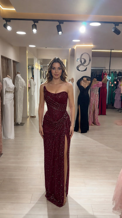 Model wearing burgundy wine red one-shoulder sequin evening gown