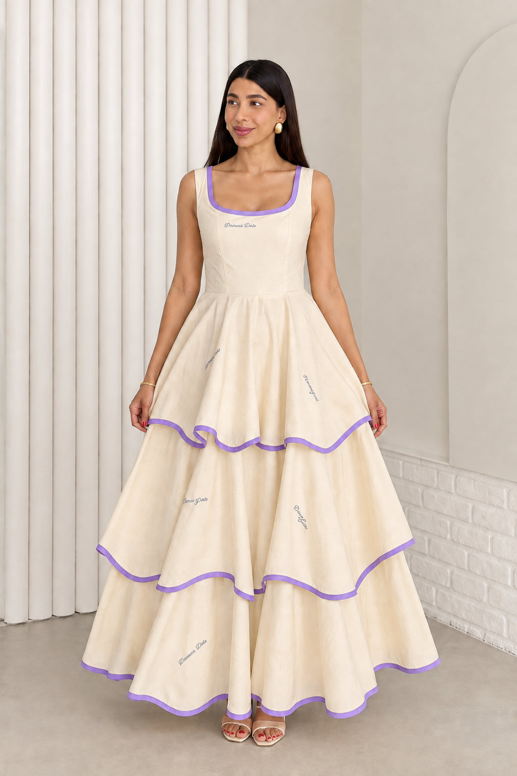 Model wearing cream sleeveless tiered maxi dress with purple contrast trim